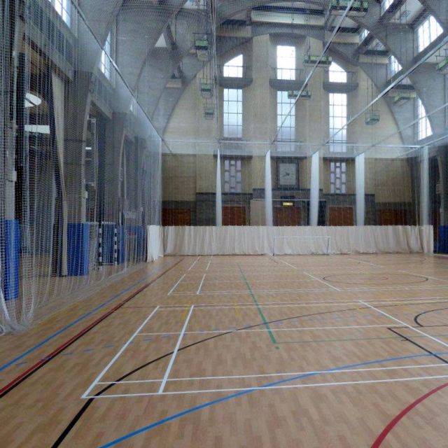 A sports hall with the perimeter netting pulled out ready for the game of cricket